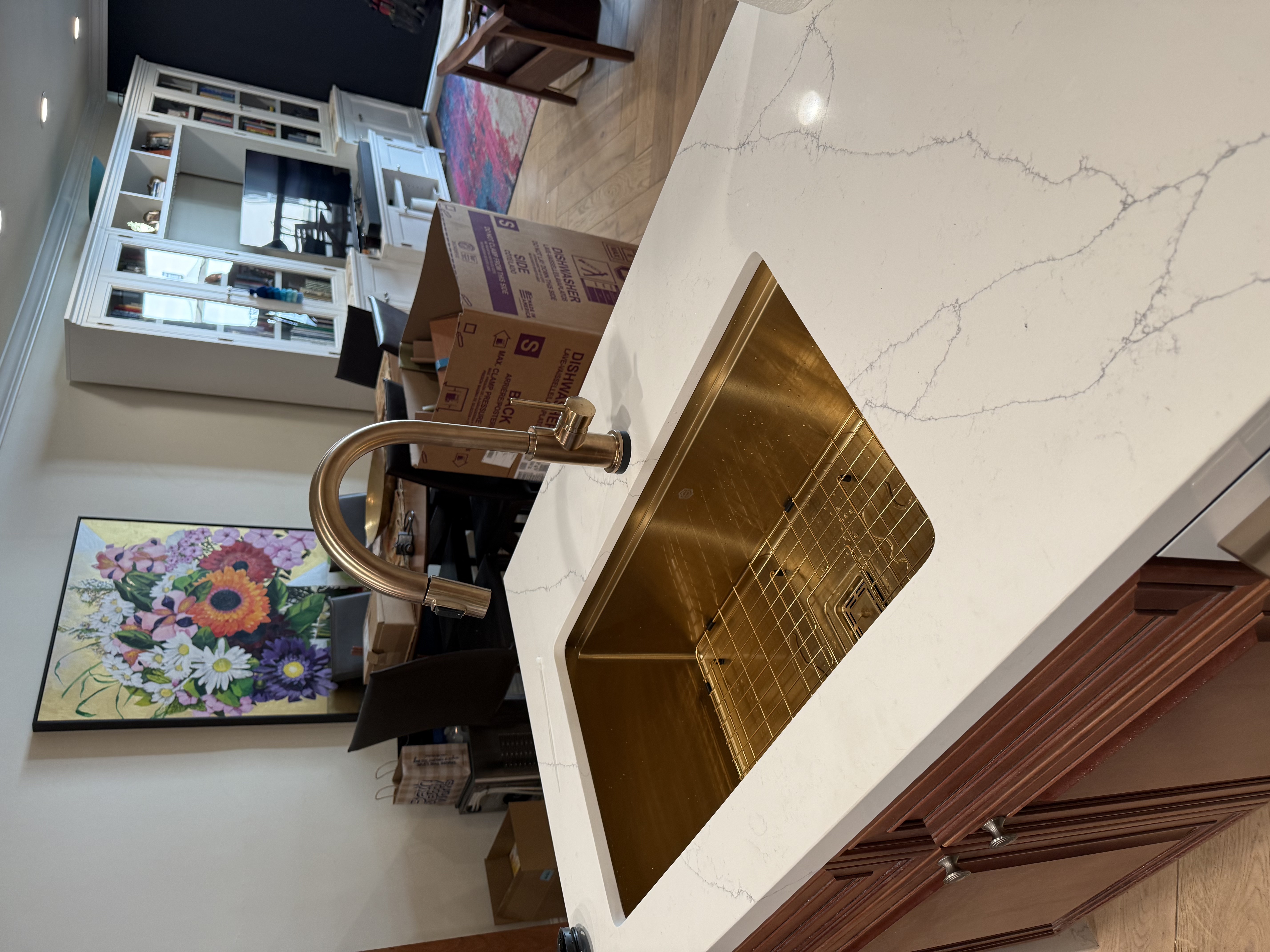 Gold kitchen sink with pull-down faucet installed in marble island