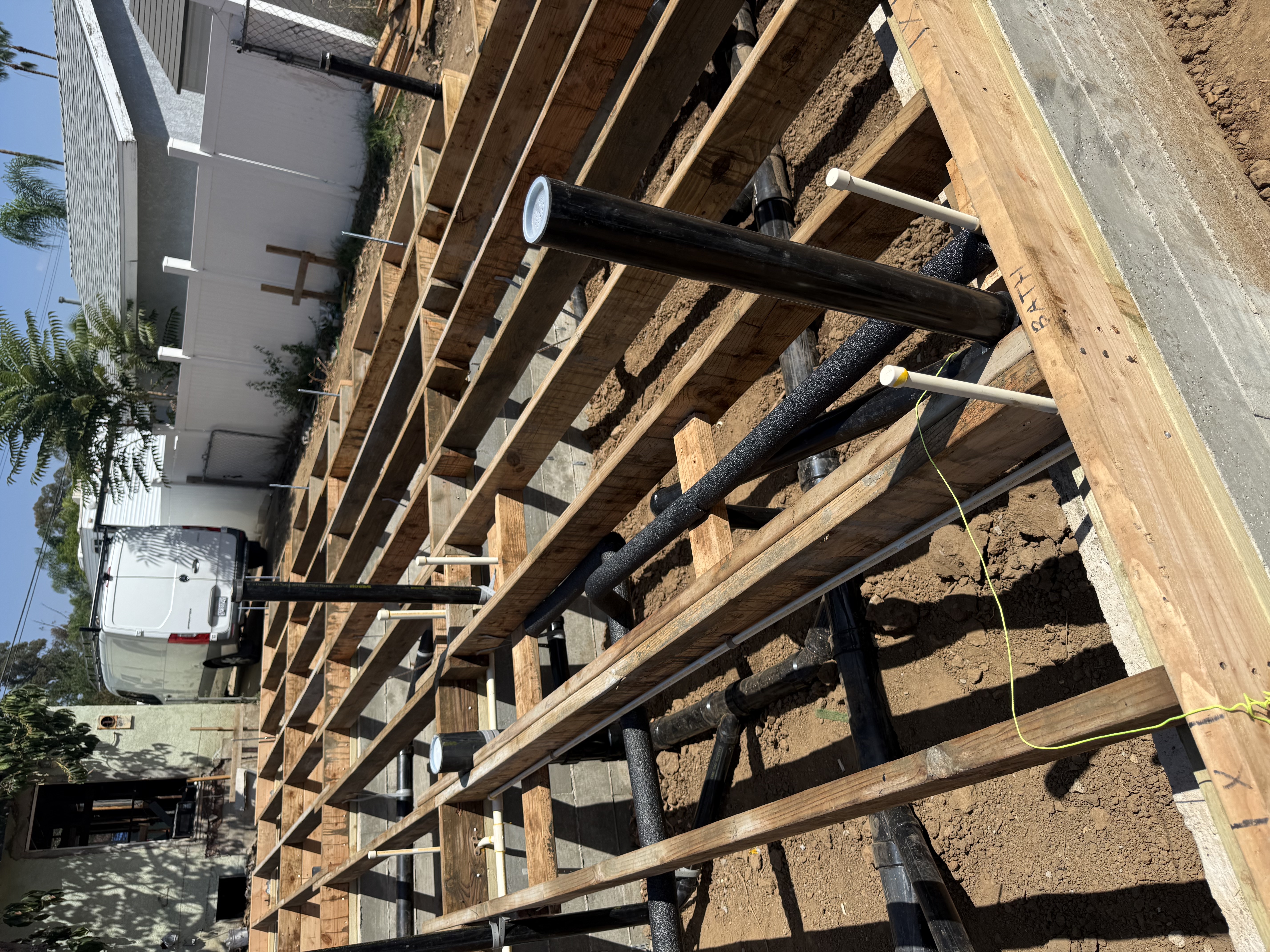 Underground plumbing stub-outs beneath subfloor framing for new 2-unit construction