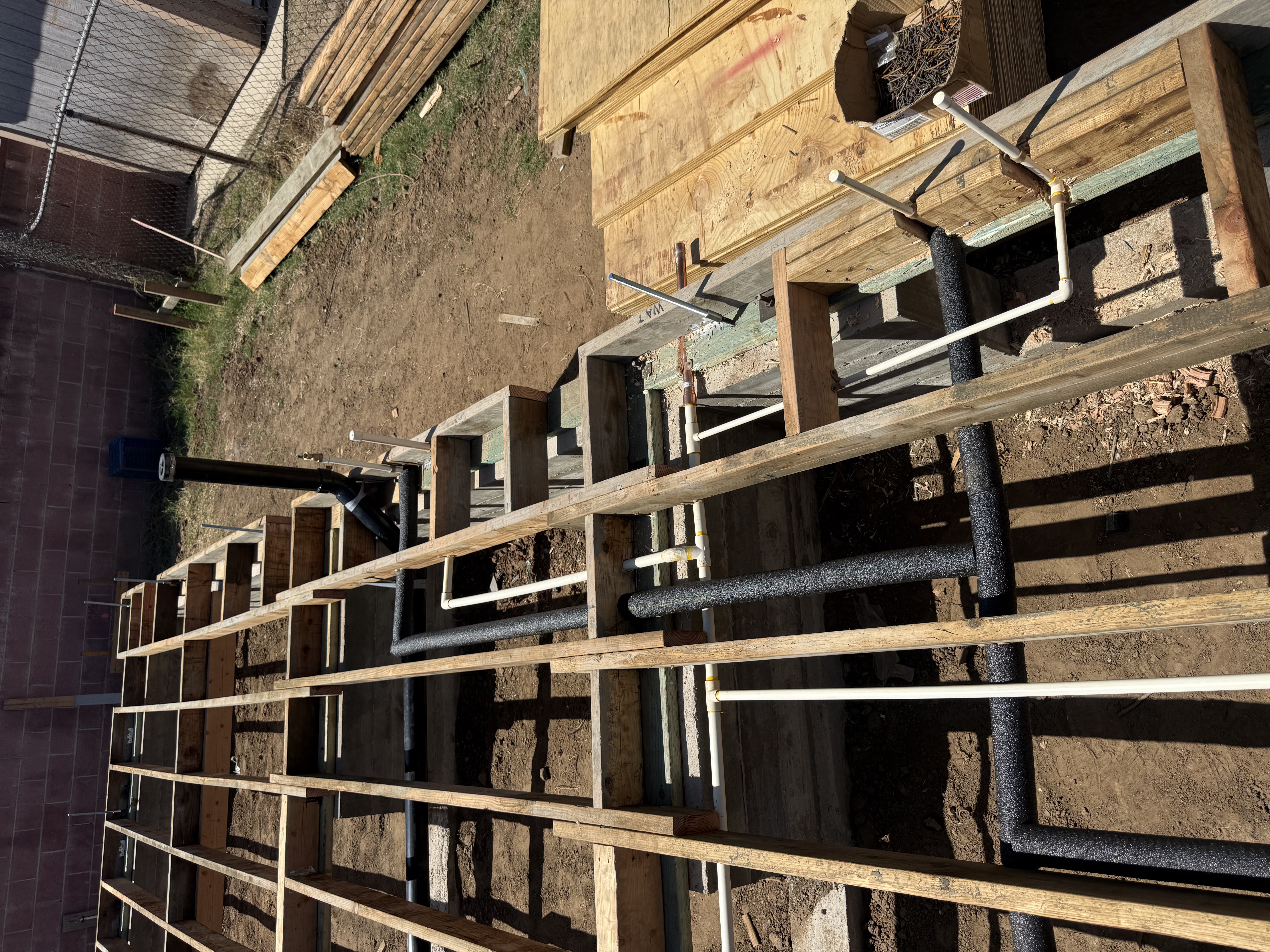 Underground plumbing rough-in stub-outs across new construction subfloor